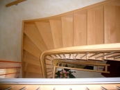 Blick von oben in ein Treppenhaus mit Holztreppe
